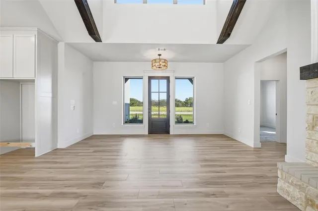 a view of an empty room with window and wooden floor