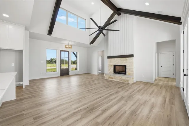 a view of an empty room with wooden floor fireplace and a window