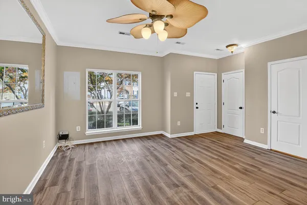 a view of an empty room with a window and wooden floor