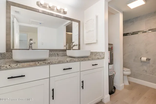 a bathroom with a granite countertop sink mirror vanity and toilet