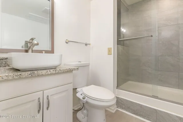 a bathroom with a granite countertop sink toilet a mirror and shower