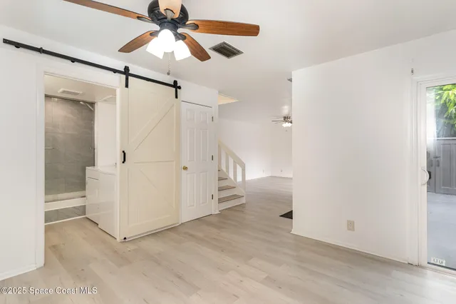 a view of a room with white walls and ceiling fan