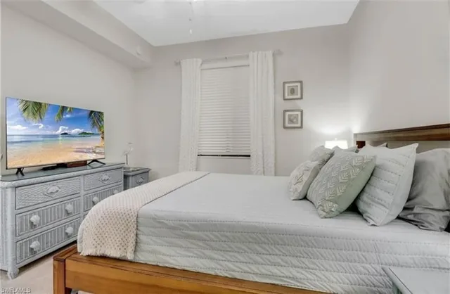 a bedroom with a large bed and a flat tv screen on dresser