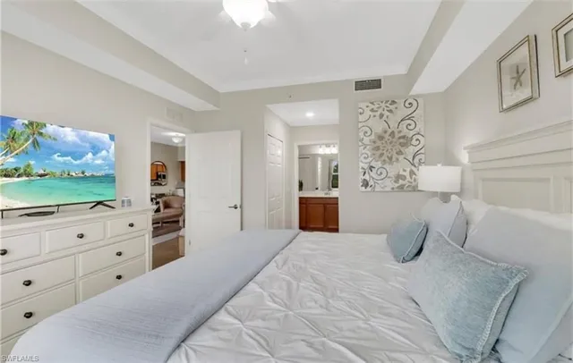 a large white bed in a bedroom and dresser