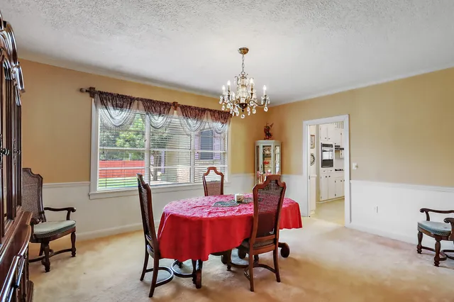 a view of a dining room with furniture a chandelier and window