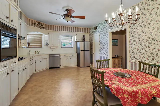 a spacious bedroom with a bed a chandelier and a flat tv screen