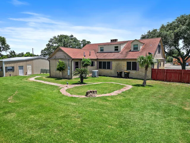 a view of a white house with a big yard and potted plants