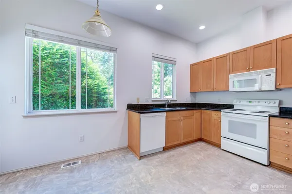 a kitchen with stainless steel appliances granite countertop a stove a sink and a microwave