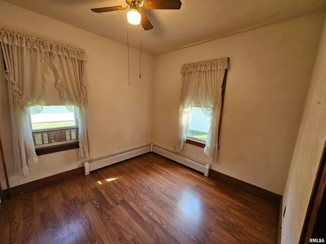 an empty room with wooden floor fan and windows