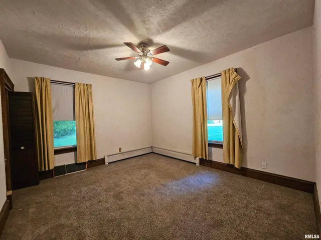 an empty room with windows and fan