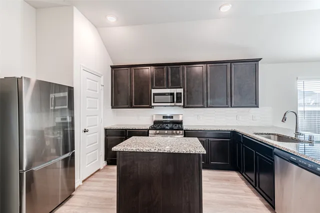 a kitchen with granite countertop a stove a sink and a microwave