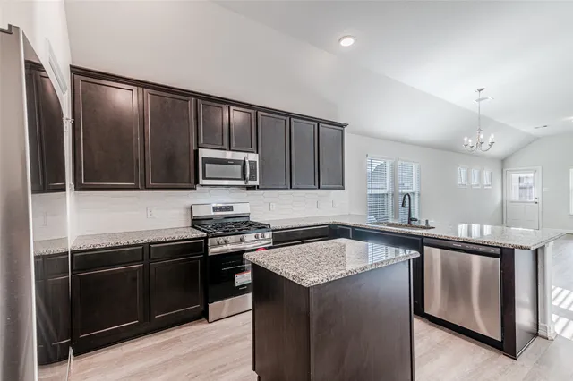 a kitchen with stainless steel appliances granite countertop a stove a sink and a refrigerator