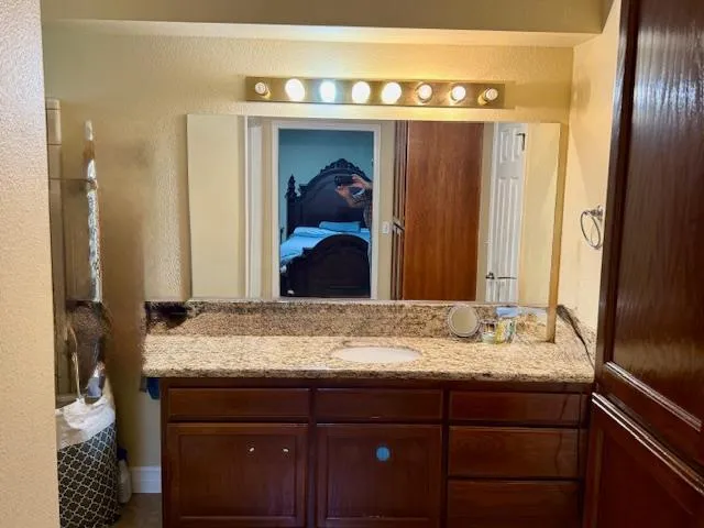 a bathroom with a granite countertop sink and a mirror