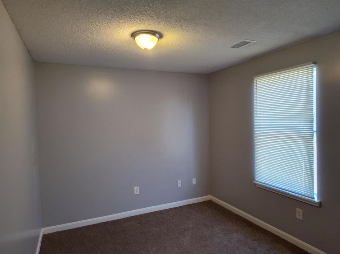 Empty room featuring a textured ceiling and dark carpet