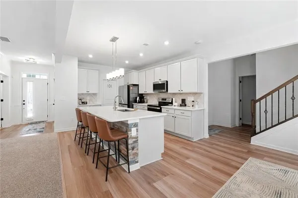 a kitchen with a dining table chairs wooden floor cabinets and a window