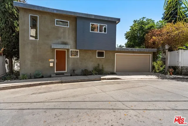 a front view of a house with garage and plants