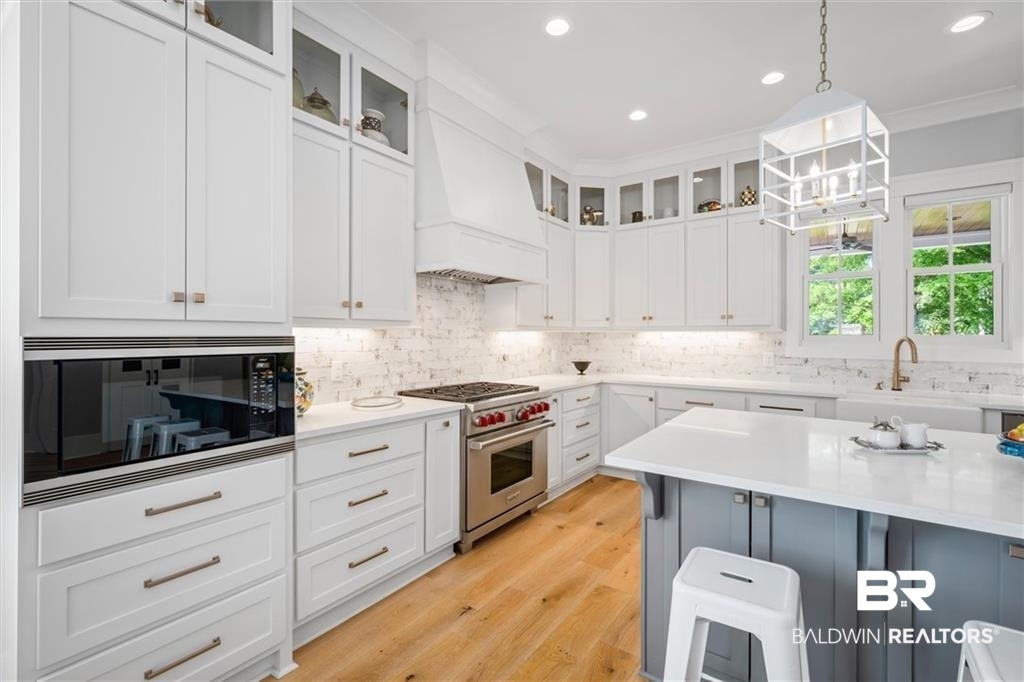 707 Cardamel Court Fairhope, AL 36532 - Photo 10 of 40 Kitchen with white cabinetry, custom range hood, light wood-type flooring, luxury stove, and black microwave
