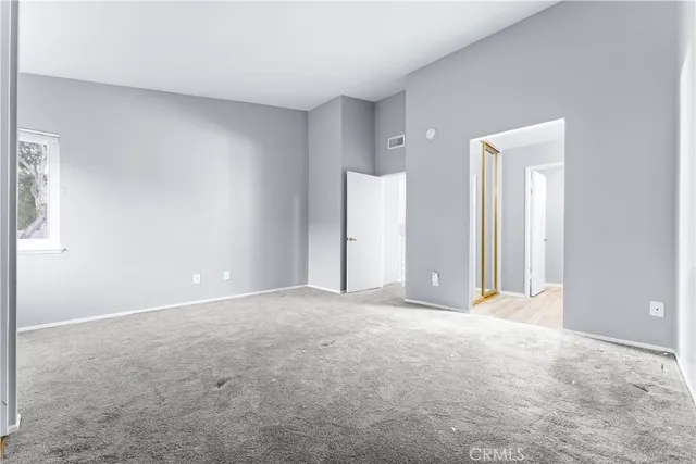 a view of an empty room with closet and a window