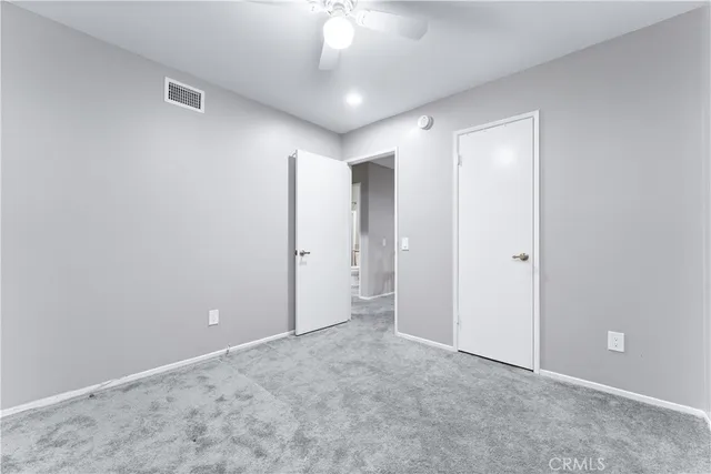 a view of an empty room and a chandelier fan