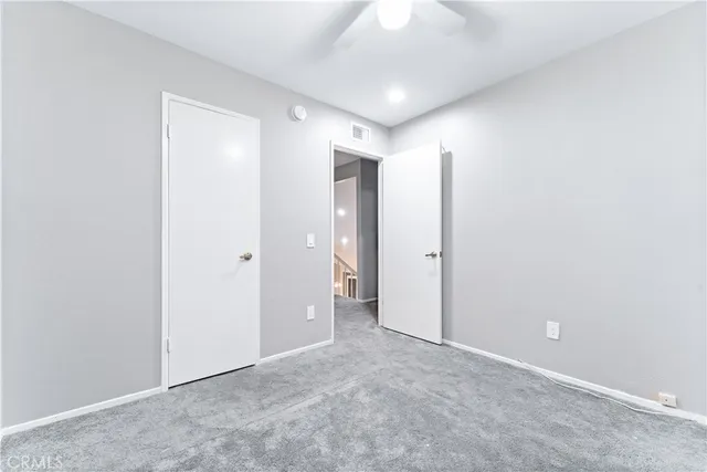 an empty room with closet and a chandelier fan