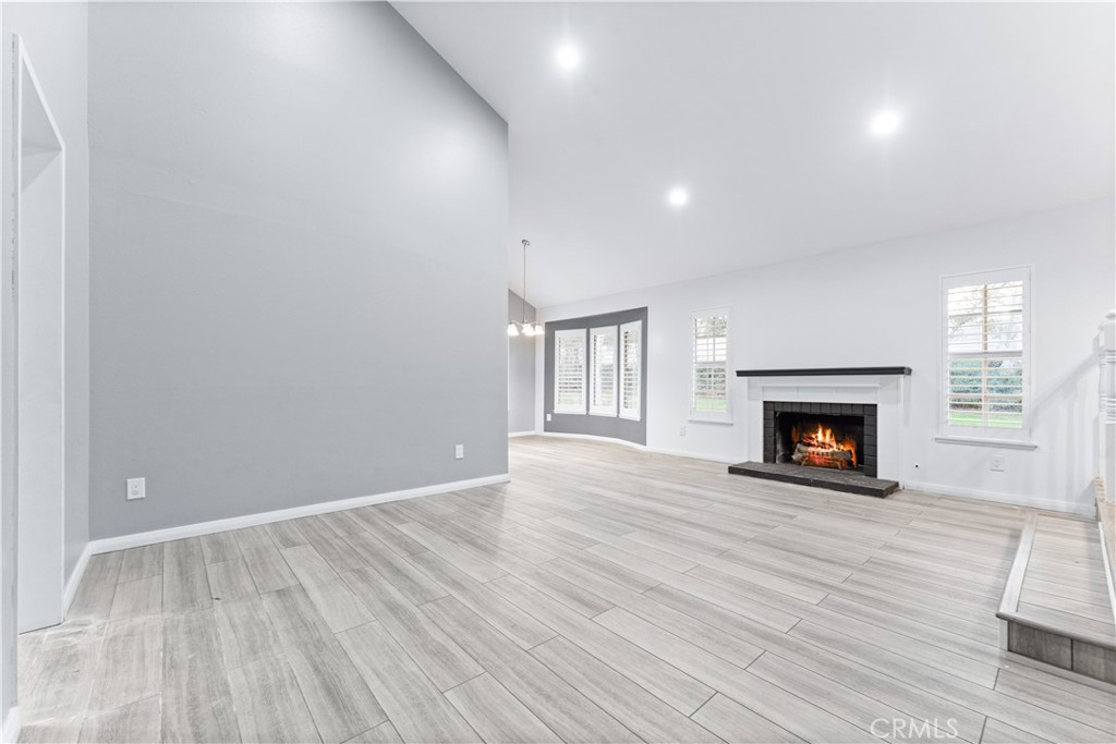 83 Weepingwood, Unit 35 Irvine, CA 92614 - Photo 5 of 19 an empty room with wooden floor fireplace and windows