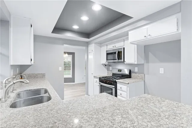 a kitchen with granite countertop a sink stainless steel appliances and cabinets