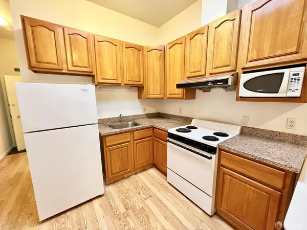a kitchen with granite countertop a refrigerator a stove a sink and cabinets