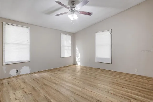 a view of an empty room with window and wooden floor
