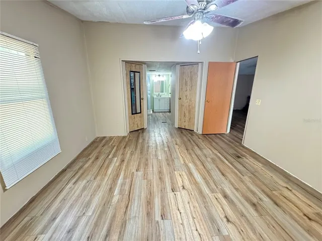 a view of a room with wooden floor fan and windows