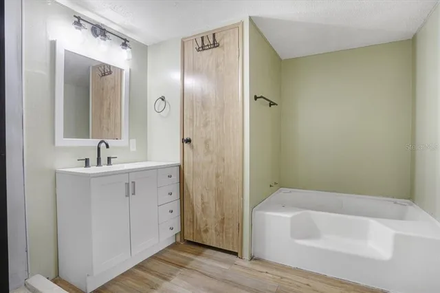 a bathroom with a tub shower sink and mirror