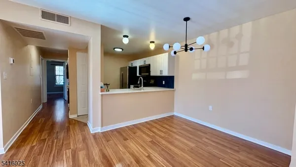 a large white kitchen with a sink and dishwasher a refrigerator with wooden floor