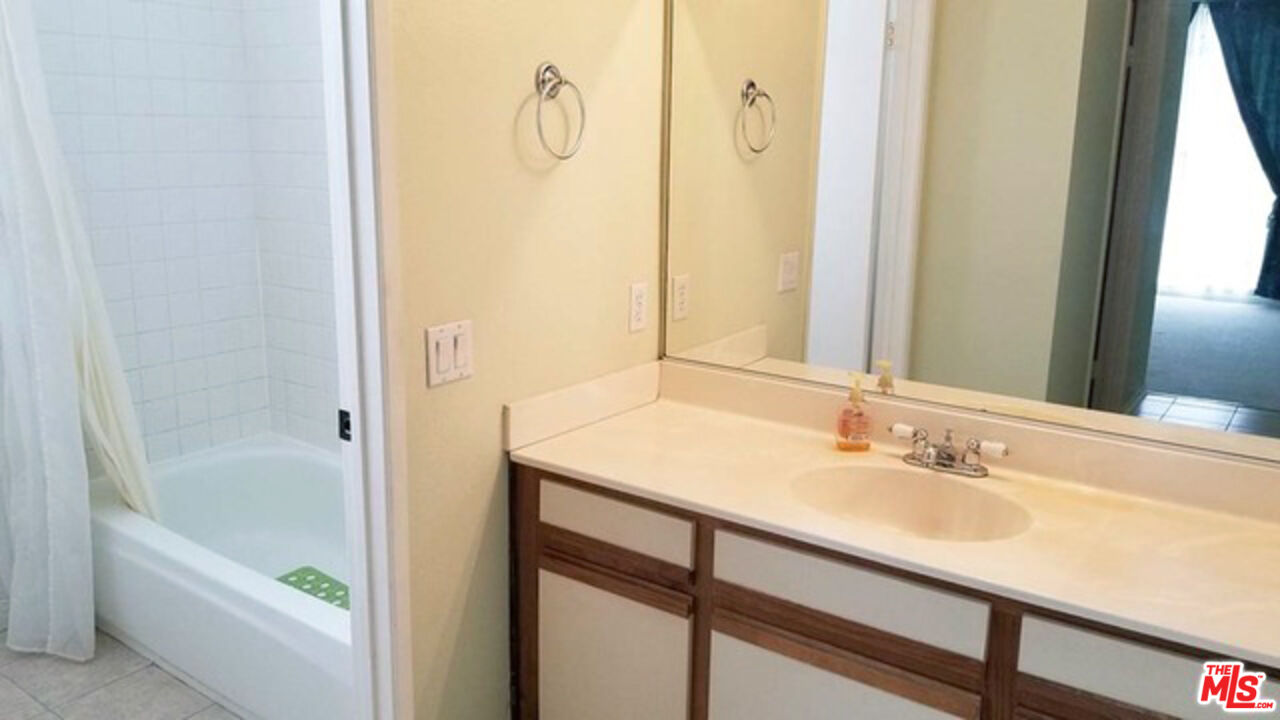 533 South St Andrews Place, Unit 321 Los Angeles, CA 90020 - Photo 11 of 16 a bathroom with a granite countertop sink a mirror and a bathtub