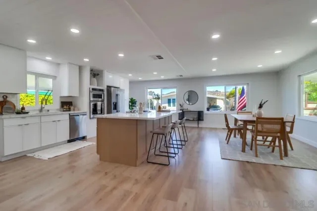a living room with furniture kitchen view and a wooden floor