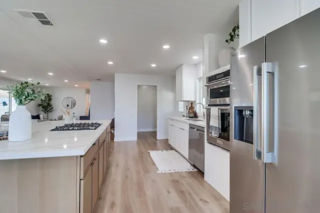 a kitchen with stainless steel appliances kitchen island granite countertop a refrigerator a stove top oven a sink dishwasher and wooden floor