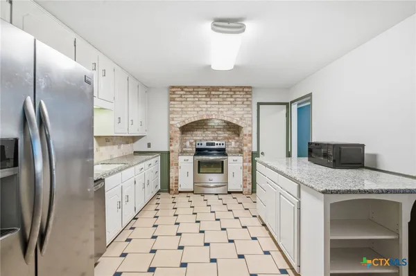 a kitchen with granite countertop a stove sink and refrigerator