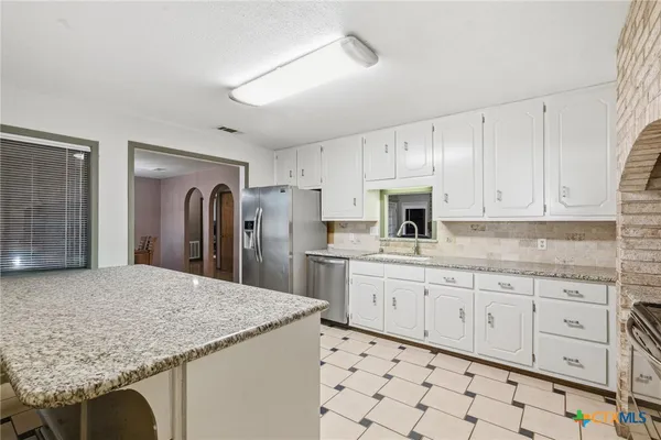a kitchen with granite countertop white cabinets and stainless steel appliances