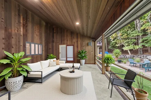 a living room with patio furniture and potted plants