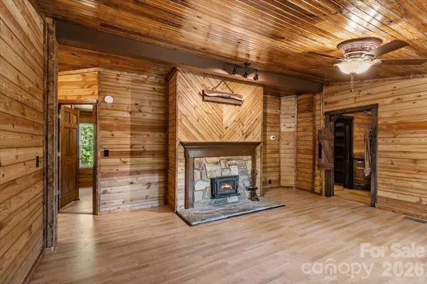 an empty room with wooden floor fireplace and windows