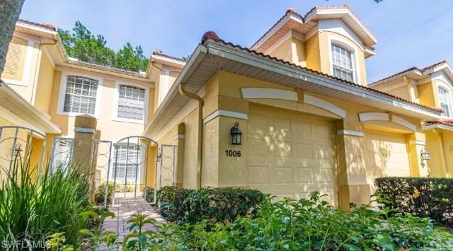 a view of a blue house with large windows and flower plants