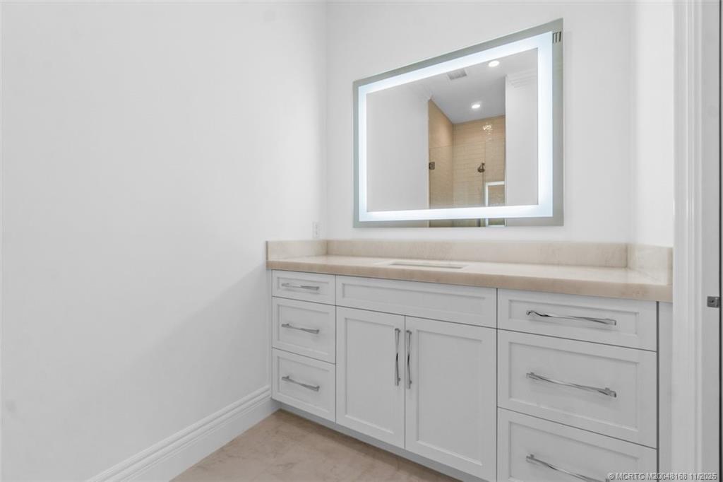 1904 Southeast Sailfish Point Boulevard Stuart, FL 34996 - Photo 32 of 64 a bathroom with a sink vanity and mirror