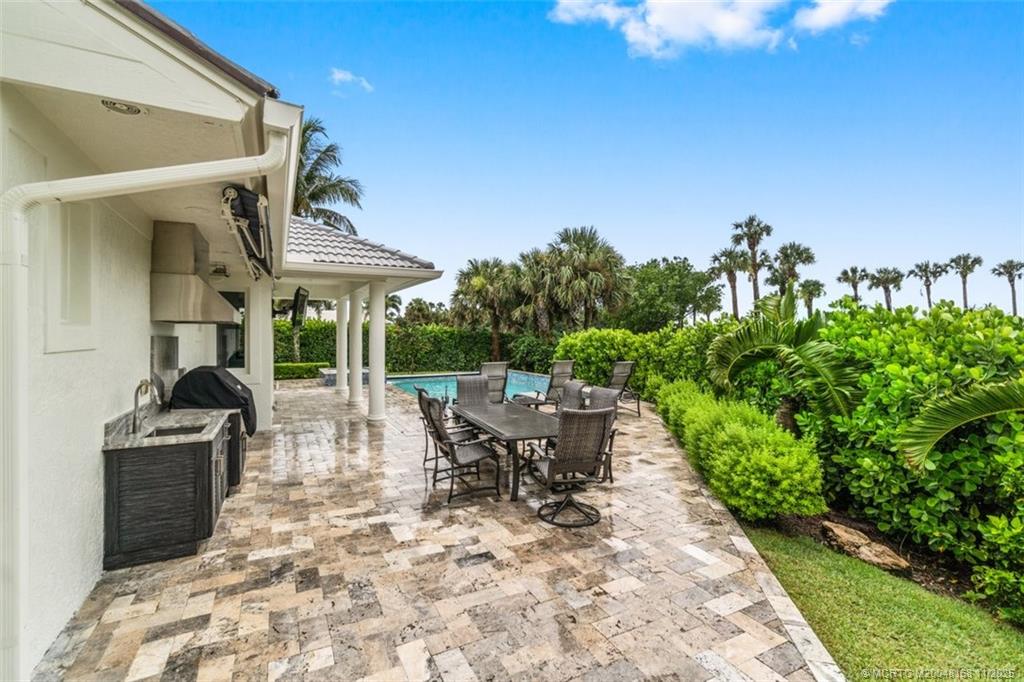 1904 Southeast Sailfish Point Boulevard Stuart, FL 34996 - Photo 50 of 64 a view of a patio with table and chairs potted plants with floor to ceiling window