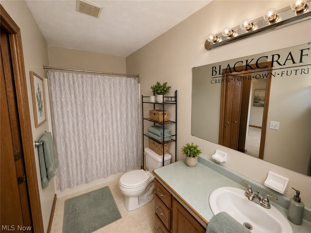 6416 Ridgeview Avenue Youngstown, OH 44515 - Photo 7 of 15 Bathroom featuring a single vanity with an integrated sink, a large wall-mounted mirror, and a shower-over-tub with a patterned curtain