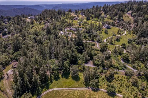 an aerial view of residential house with parking and trees