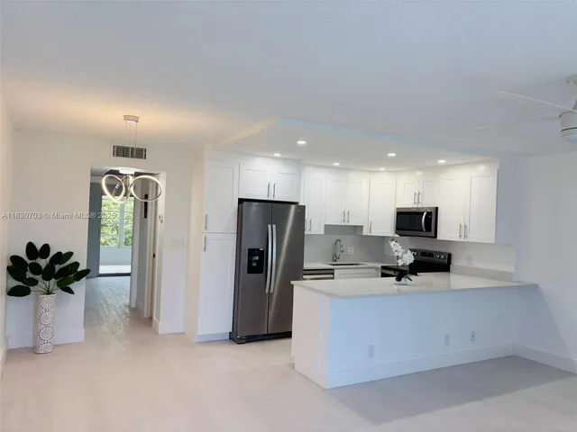 a view of a kitchen with refrigerator and white cabinets