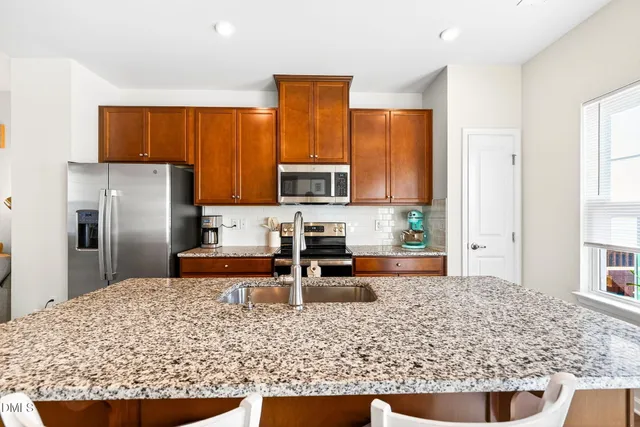 a kitchen with stainless steel appliances granite countertop a refrigerator and a sink