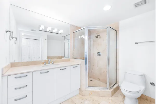 a bathroom with a granite countertop sink a toilet and shower
