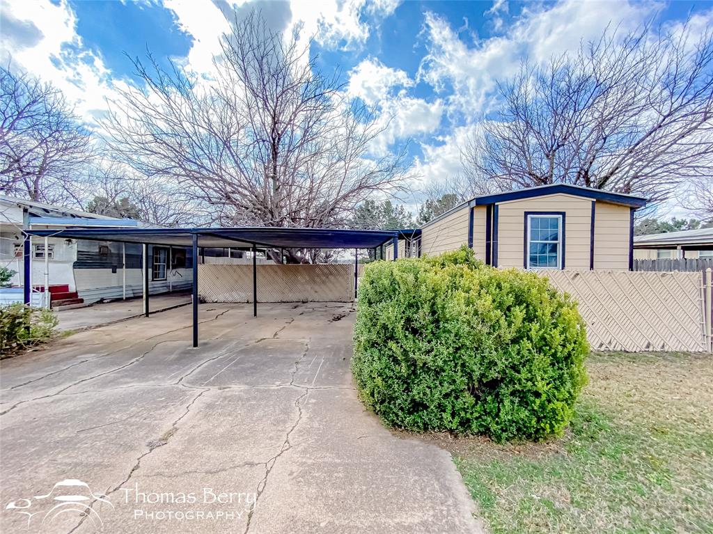 a view of a house with a yard and large tree