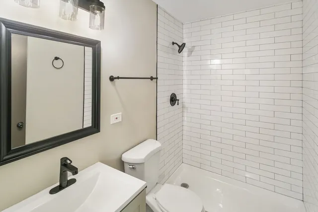 a bathroom with a toilet a sink a shower and mirror