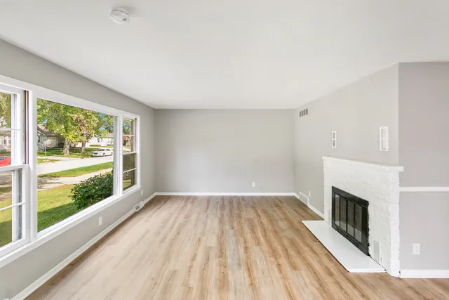 a view of empty room with wooden floor and fireplace