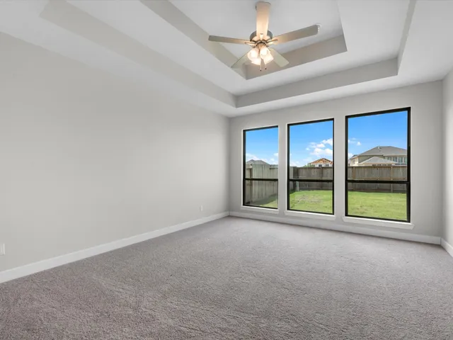 an empty room with windows and ceiling fan
